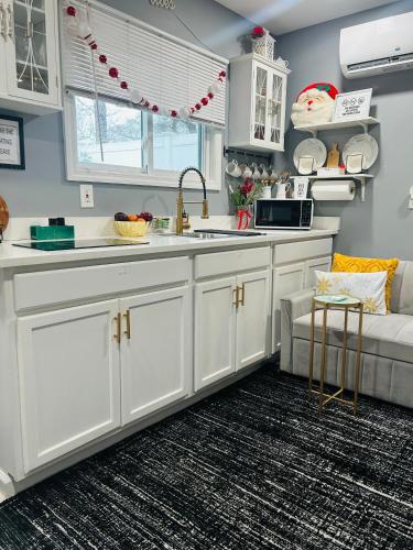 a kitchen with white cabinets and a couch in a room at Fancy Studio Private Entrance in Selden