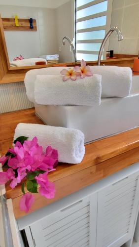 een wastafel met handdoeken en bloemen op een aanrecht bij Le chant du Lagon in La Saline les Bains