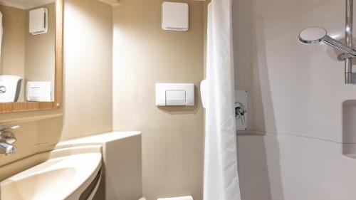 a bathroom with a shower and a sink at Premiere Classe Valenciennes Ouest Petite Foret in Petite Forêt