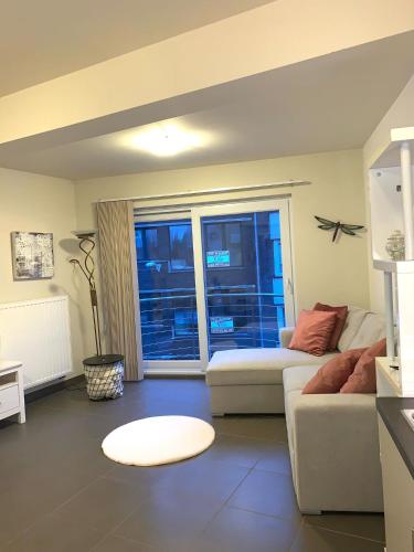 a living room with a white couch and a window at Stijlvol appartement in hartje Oostende vlak bij het strand en de winkelstraat - 6p in Ostend