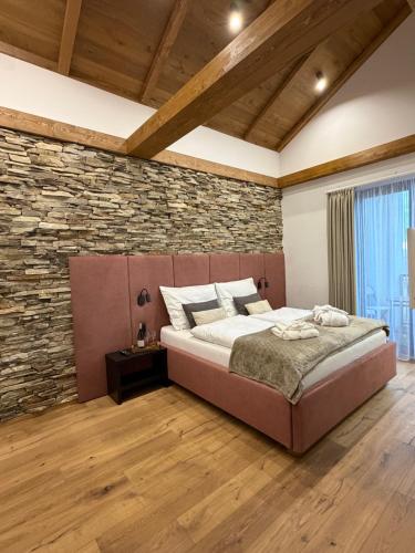ein Schlafzimmer mit einem großen Bett und einer Steinwand in der Unterkunft Vila Vento in Veľký Slavkov