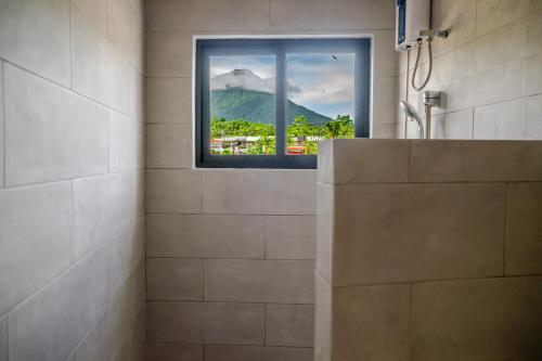 Un baño con vista a una montaña a través de una ventana. en Hotel Arenal by Regina, en Fortuna