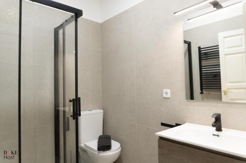 un bagno con un water, un lavandino e uno specchio di Malasaña Urban Rooms a Madrid
