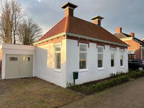 a white house with a red roof and a garage at Het Witte Huisje in Ezinge