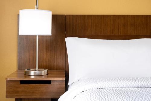 a bed with a wooden headboard and a table with a lamp at Garner Hotel Victoria - East by IHG in Victoria