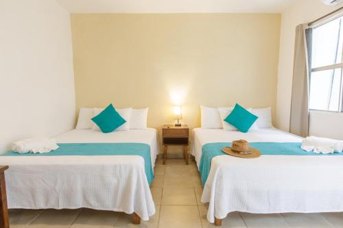 two beds in a room with a hat on top at La Diosa Kali Beach Front Hotel in Holbox Island
