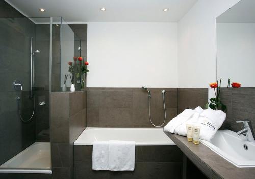 a bathroom with a bath tub and a sink at Hotel Regina - Bed & Breakfast Köln in Cologne