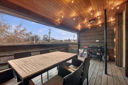eine Terrasse mit Holztisch und Stühlen sowie einem Grill in der Unterkunft The Loft in Whitefish