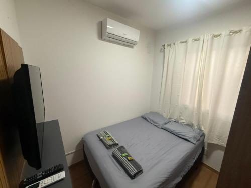 a small room with a bed and a television at Recanto Augusta in Londrina