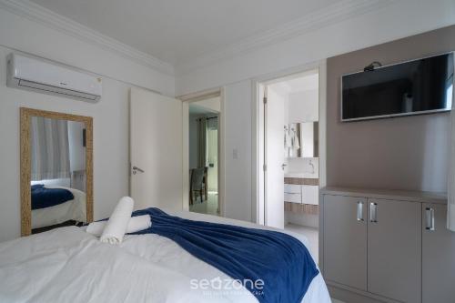 ein Schlafzimmer mit einem Bett und einem Fernseher an der Wand in der Unterkunft Apto 2Q c/ churrasq. no centro - Bombinhas CAA103 in Bombinhas