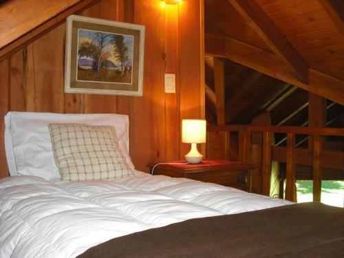 Un dormitorio con una cama y una lámpara sobre una mesa. en Las Bahías, en Villa La Angostura