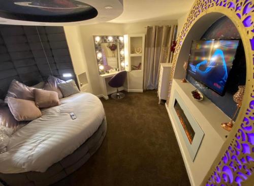 a bedroom with a bed and a flat screen tv at Luxury Suites in Bradford