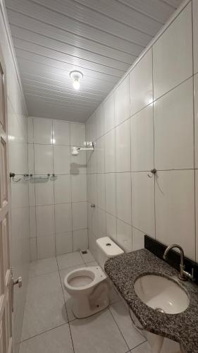 een witte badkamer met een toilet en een wastafel bij Casa Guriri in São Mateus