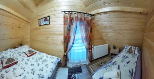 a bedroom with two beds in a wooden cabin at Cabana MARA in Poiana Vadului