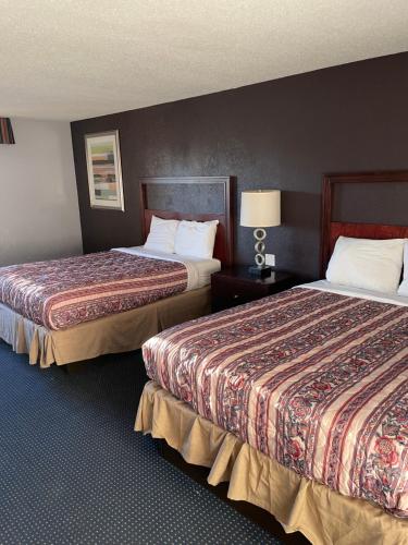 a hotel room with two beds and a lamp at Apm Inn & Suites in Hagerstown