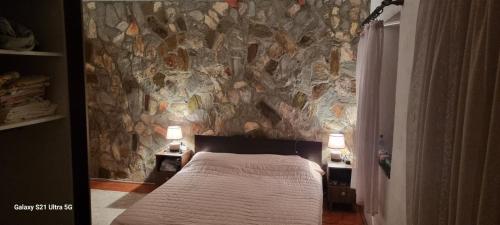 a bedroom with a stone wall with a bed at Villla Gezve in Velmevci
