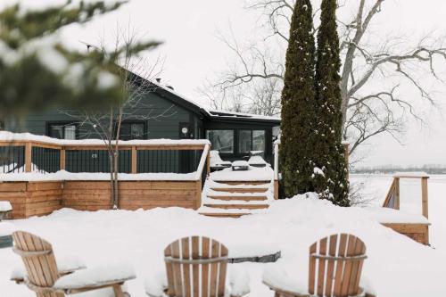 een met sneeuw bedekte tuin met twee stoelen en een huis bij Narrows Nook - Prince Edward County Waterfront in Deseronto