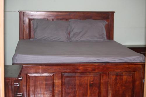 een bed met een houten hoofdeinde en een houten frame bij Wilpattu Haritha Villa in Pahala Maragahawewa