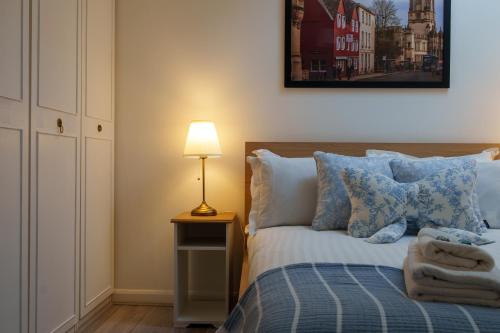 a bedroom with a bed with blue pillows and a lamp at Oxford Modern Living - Free Parking in Oxford