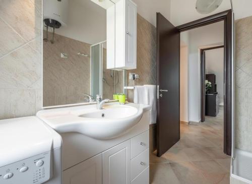 un bagno bianco con lavandino e specchio di Villa Giulietta a Castiadas