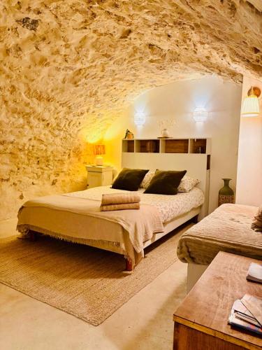 La Cueva في لا غارد-اديمار: غرفة نوم بها سريران وجدار حجري