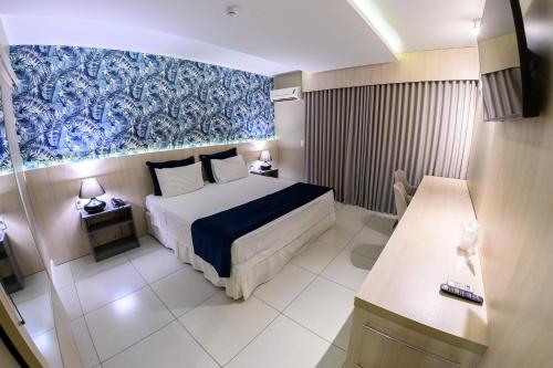 ein Hotelzimmer mit einem Bett und einem blauen Gemälde an der Wand in der Unterkunft Hotel Águas Claras in Santa Cruz do Sul