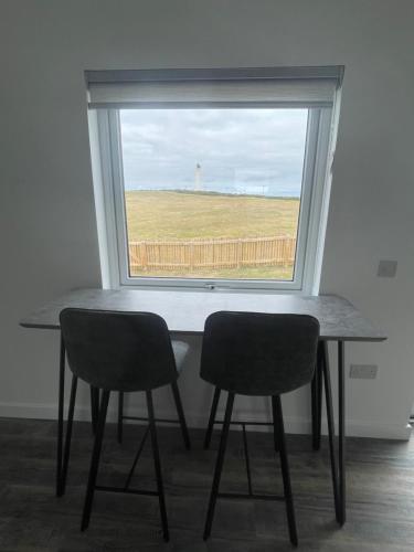 a table and two chairs in a room with a window at 1 Lighthouse View in Lossiemouth