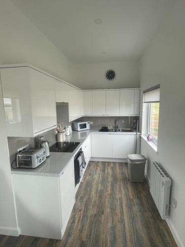 a kitchen with white cabinets and a wooden floor at 1 Lighthouse View in Lossiemouth