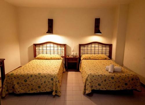 a hotel room with two beds and a desk at Hotel Plaza Independencia in Villahermosa