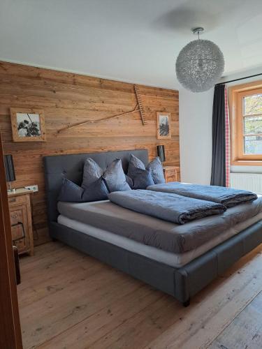 a large bed in a bedroom with a wooden wall at Tiroler Knusperhäuschen in Tannheim