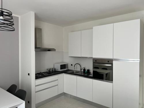 eine weiße Küche mit weißen Schränken und einer Mikrowelle in der Unterkunft Il Rifugio in Sulmona