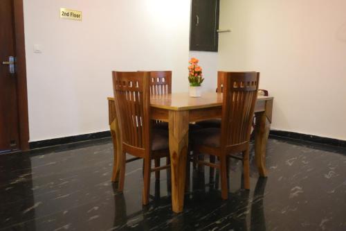 a wooden table with four chairs and a vase with flowers at Sufi Stay in Rishīkesh