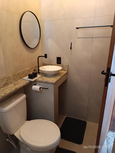 a bathroom with a toilet and a sink and a mirror at Loftshorizontedesalvina in Búzios