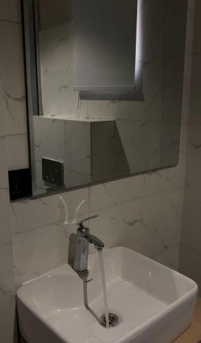 een wastafel in de badkamer met een spiegel en een kraan bij Rock Apartment in Lekki