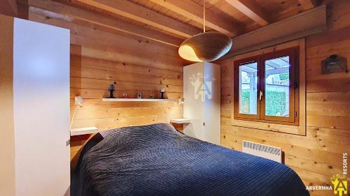 een slaapkamer met een bed in een houten kamer bij Chalet de Cécile 1 in Besse-et-Saint-Anastaise