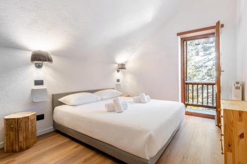 une chambre avec un grand lit blanc et une fenêtre dans l'établissement Hostdomus-La casa di Luna, à Grange Sises