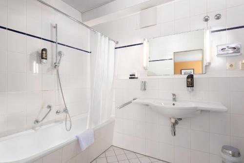 a white bathroom with a sink and a shower at Trip Inn Hotel Minerva Frankfurt in Frankfurt/Main