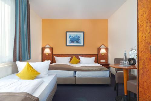 a hotel room with two beds and a table at Trip Inn Hotel Minerva Frankfurt in Frankfurt/Main