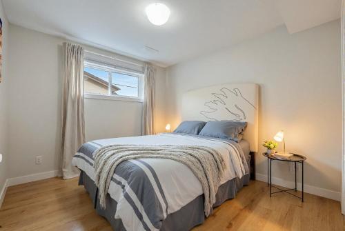 a bedroom with a large bed and a window at Cozy and Welcoming 2BR Basement Suite In The Heart of Calgary in Calgary