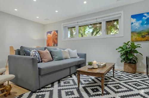 a living room with a gray couch and a table at Cozy and Welcoming 2BR Basement Suite In The Heart of Calgary in Calgary