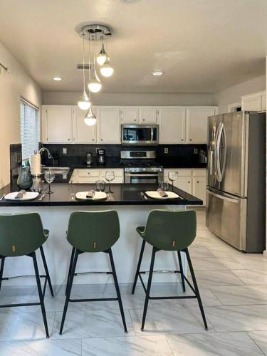 a kitchen with a large counter with chairs and a refrigerator at 3BR - 3BA w Pool & BBQ -15 Mins to Strip & Airport in Las Vegas