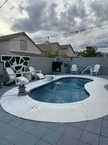 a swimming pool with white chairs and a patio at 3BR - 3BA w Pool & BBQ -15 Mins to Strip & Airport in Las Vegas