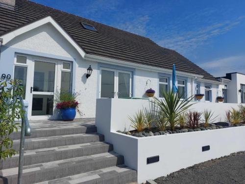 a white house with stairs in front of it at Rest A While in Bushmills