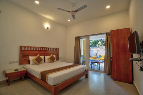 ein Schlafzimmer mit Bett, Fernseher und Balkon in der Unterkunft Goa Radha Krishna holiday in Calangute