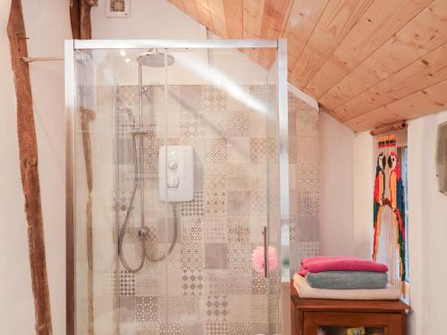 una doccia con una porta in vetro in un bagno di The Hare & The Bumblebee Cottage a Hoxne