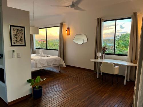 a room with a bed and a table and windows at Villas Jacquelina in Quepos