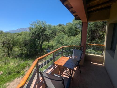 a balcony with a wooden table and chairs on it at Posada Abrazo Serrano en Carpintería in Carpintería
