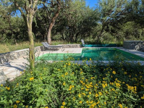 a swimming pool in a garden with flowers at Posada Abrazo Serrano en Carpintería in Carpintería