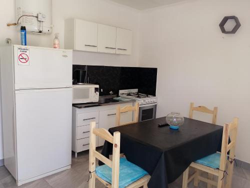eine Küche mit einem schwarzen Tisch und einem weißen Kühlschrank in der Unterkunft Departamento NAMASTE I in Carhué