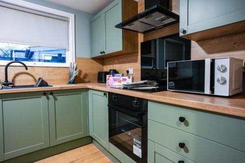 a kitchen with green cabinets and a microwave at Victory House in Gretna
